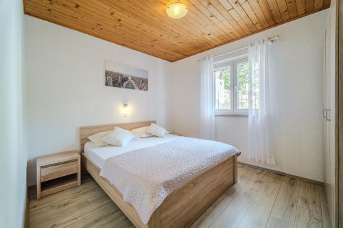 a bedroom with a bed with a wooden ceiling at Robinson Eda in Murvica