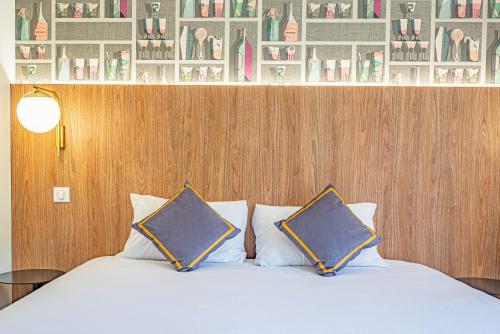 a bedroom with a bed with two pillows on it at Kyriad Aix Les Milles - Plan de Campagne in Bouc-Bel-Air