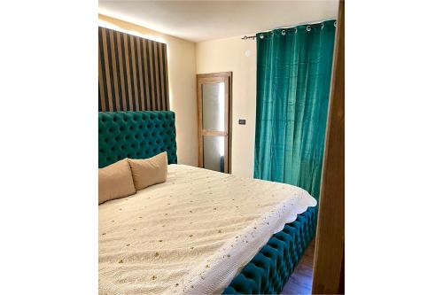 a bedroom with a bed with a blue headboard and curtains at Loft Apartman Menhetn in Šabac