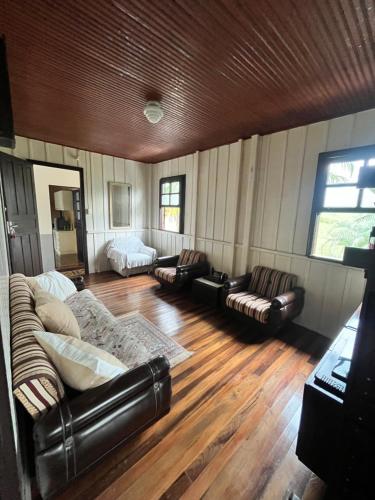 sala de estar con muebles de cuero y suelo de madera en Morada Ignese, en Siderópolis