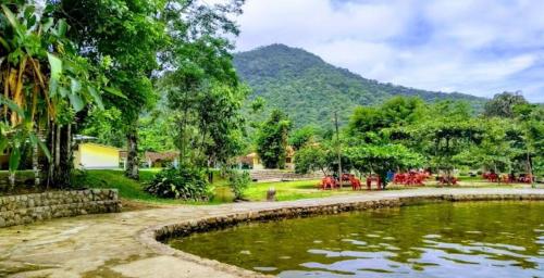 un estanque en un parque con una montaña al fondo en Traillertuba Yaveh, en Ubatuba