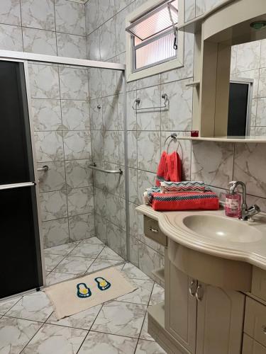 ein Bad mit einer Dusche und einem Waschbecken in der Unterkunft Morada Ignese in Siderópolis