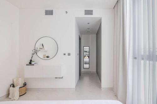 a hallway with white walls and a mirror and a mirror at HiGuests - Step Into Heaven In This Lakeside Apartment in Dubai
