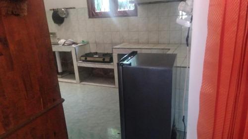 a kitchen with a black refrigerator and a stove at Jaya Bersama Home stay in Baso