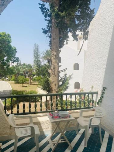 a table and chairs on a balcony with a tree at Studio bord de mer à louer in Hammam Sousse