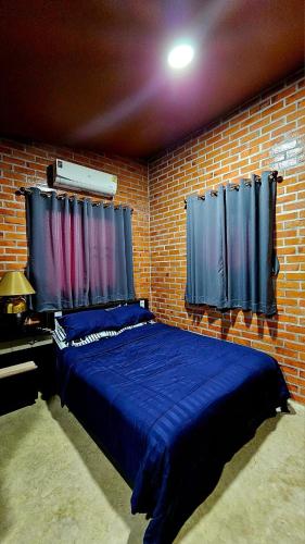 1 dormitorio con 1 cama azul en una pared de ladrillo en บ้านสวนลุงแจน ฟิชชิ่งพาร์ค แอนด์ รีสอร์ท, 