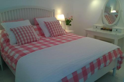 - un lit avec une couverture rouge et blanche en damier et un miroir dans l'établissement Villa 3, Port Nature au village naturiste, au Cap d'Agde