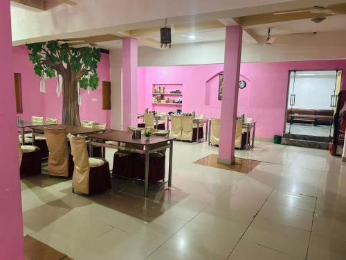 a restaurant with pink walls and a table with chairs at Hotel Maurya Vihar Bodhgaya in Bodh Gaya