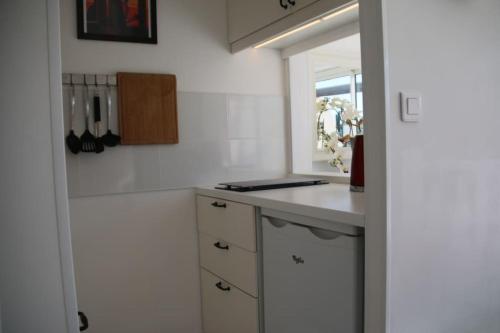 une cuisine blanche avec un comptoir et une fenêtre dans l'établissement Villa 3, Port Nature au village naturiste, au Cap d'Agde