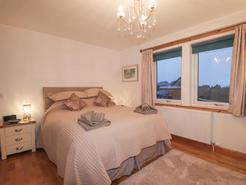 - une chambre avec un lit, un lustre et deux fenêtres dans l'établissement Roselea, à Broadford