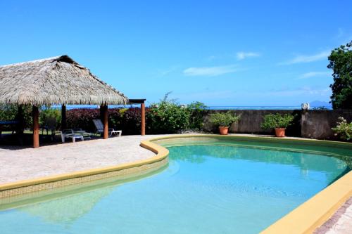 a swimming pool with a straw umbrella next to a beach at Arahea Lagoon flat beachfront with pool facing the sunset Wi-Fi - AC in Paea