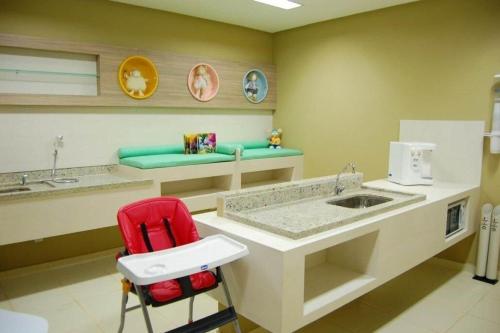 a bathroom with a counter with a sink and a red chair at Apartamentos em Rio Quente com maravilhosa área de lazer e linda vista in Rio Quente