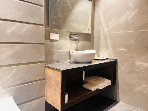 a bathroom with a sink on a wooden shelf at Airport Hotel Nysha Palace in New Delhi