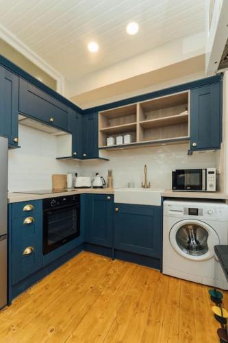 a kitchen with blue cabinets and a washing machine at James Street 2 Bedroom Apartment in Stirling