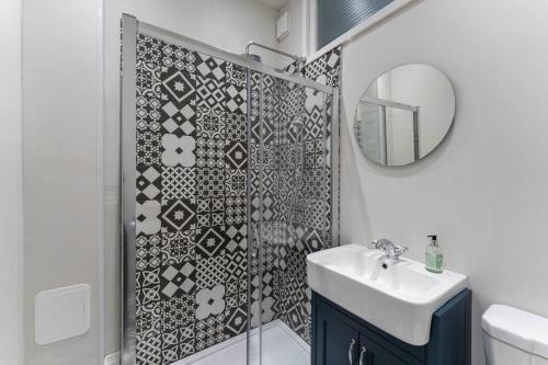a bathroom with a shower with a sink and a mirror at Beautifully Renovated 2 Bedroom Apartment in Stirling
