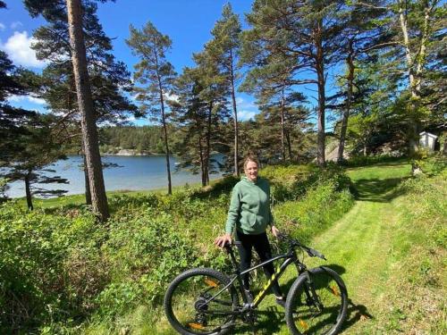 a man standing next to a bike in a field at Luxury 3 Bedroom Modern House in Nature in Uddevalla