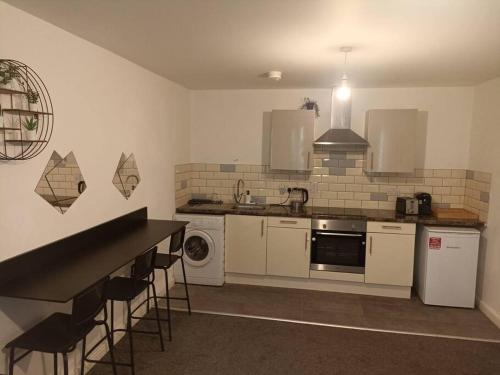 a kitchen with white appliances and a counter with stools at The Boat House 107 in Leicester