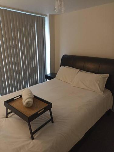 een bed met een houten dienblad met een handdoek erop bij The Boat House 107 in Leicester
