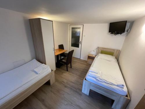 プラハにあるPenzion Nová Hospodaのベッド2台、デスクが備わる小さな客室です。
