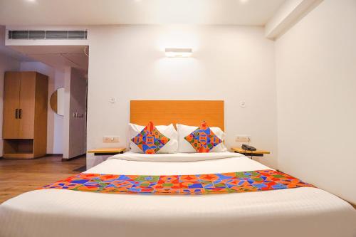 a bedroom with a large white bed with colorful pillows at FabHotel Ramayana in Vibhuti Khand