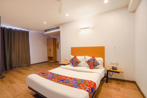 a bedroom with a large white bed with colorful pillows at FabHotel Ramayana in Vibhuti Khand