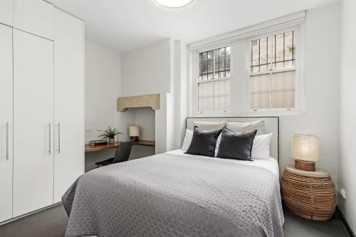 a white bedroom with a bed and a desk at Balmain Wharf 1 bedroom Apartments in Sydney
