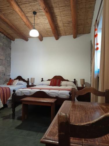 1 dormitorio con 2 camas, mesa y banco en La Casa del Indio en Tilcara