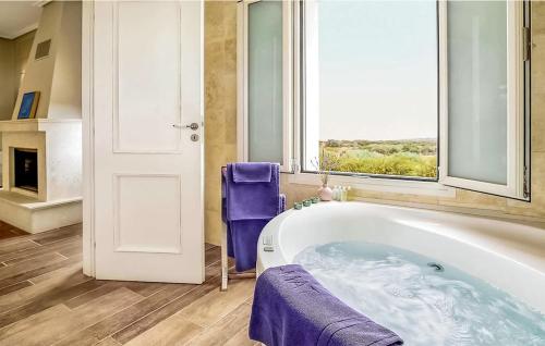 ein Bad mit einer Badewanne und einem Fenster in der Unterkunft Splendid Kefalonia Villa - 3 Bedrooms - Villa Mandola - Great Sea and Mountain Views - Trapezaki in Kefalonia