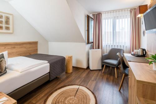 Habitación de hotel con cama y escritorio en Neo Hotel Linde Esslingen, en Esslingen