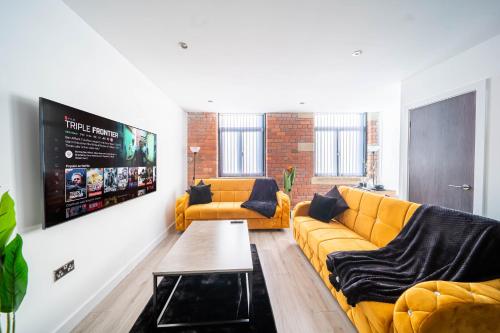 a living room with a yellow couch and a tv at Fancy 2-Bedroom Apartment with 2 Bathrooms in Bradford Town Centre in Bradford