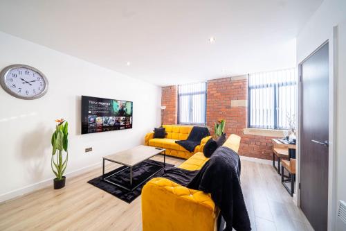 a living room with two yellow couches and a clock at Fancy 2-Bedroom Apartment with 2 Bathrooms in Bradford Town Centre in Bradford