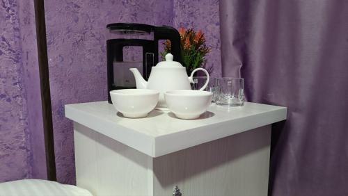 a table with two white bowls and a tea kettle at DAVR хостел in Namangan