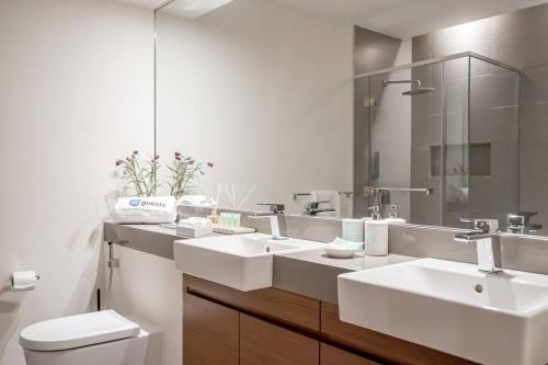 a bathroom with two sinks and a toilet and a mirror at HiGuests - Magnificent Apt with Panoramic Views All Around in Dubai