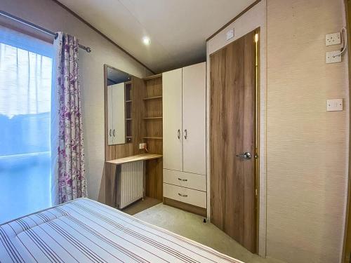 ウィスタブルにあるLovely 6 Berth Caravan With Decking And Wifi In Kent, Ref 47017cのベッドルーム1室(ベッド1台、クローゼット、ドア付)