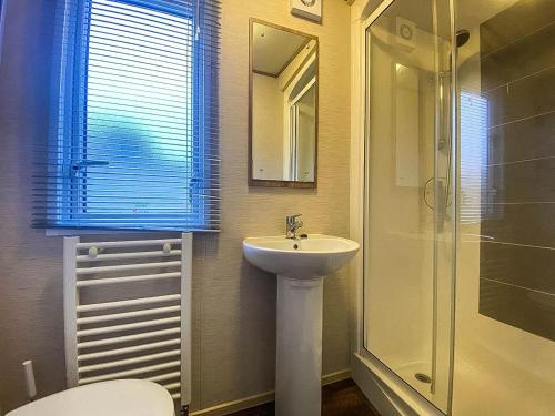 y baño con lavabo, aseo y ducha. en Lovely 6 Berth Caravan With Decking And Wifi In Kent, Ref 47017c en Whitstable