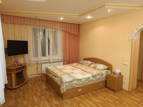 um quarto com uma cama e uma televisão de ecrã plano em Cozy apartments on Lushpy Avenue em Sumy