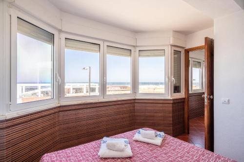 a bedroom with two beds in a room with windows at Akisol Caparica Alive in Costa da Caparica