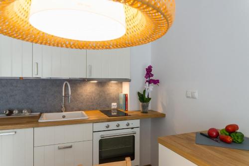 uma cozinha com armários brancos e uma grande luminária em VacationClub - Spokojna 24A Apartament D1 em Wisla