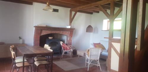 ein Wohnzimmer mit einem Kamin, einem Tisch und Stühlen in der Unterkunft Gîte de charme en pleine nature in Saint-Jean-la-Poterie