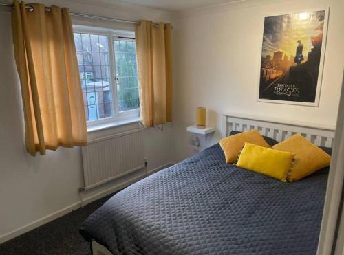 a bedroom with a bed with two yellow pillows at Spacious 5 Bedroom House- Harry potter world & London in Watford
