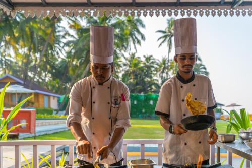 two chefs standing in a kitchen preparing food at La Cabana Beach & Spa, By Ashvem Beach in Mandrem