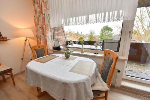 ein Esszimmer mit einem Tisch und einem Fenster in der Unterkunft Haus "Luv und Lee" Appartement LUV31 in Cuxhaven