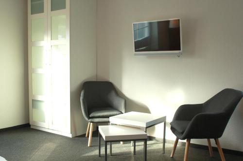 Cette chambre dispose de 2 chaises et d'une télévision murale. dans l'établissement Restaurant Ollex and beds Zimmer 2, à Bliesdorf