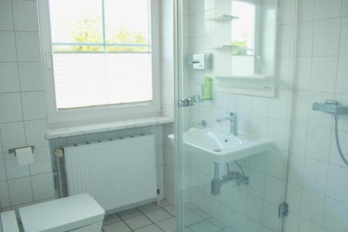 La salle de bains est pourvue d'un lavabo, de toilettes et d'une fenêtre. dans l'établissement Restaurant Ollex and beds Zimmer 2, à Bliesdorf