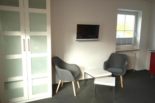 Cette chambre dispose de 2 chaises, d'une table et d'une télévision. dans l'établissement Restaurant Ollex and beds Zimmer 2, à Bliesdorf