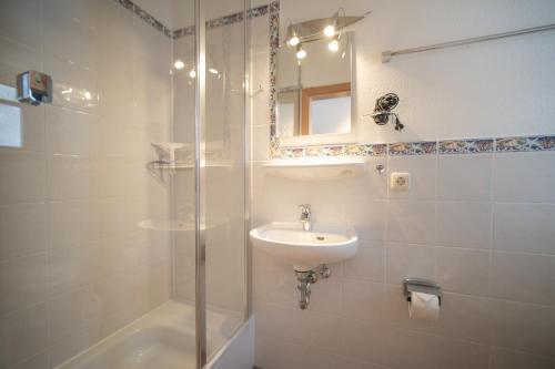 La salle de bains blanche est pourvue d'un lavabo et d'une douche. dans l'établissement Reetdachhaus Malve 2, à Puddemin