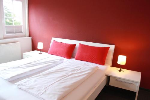 a bedroom with red walls and a white bed with red pillows at Restaurant Ollex and beds Zimmer 4 in Bliesdorf