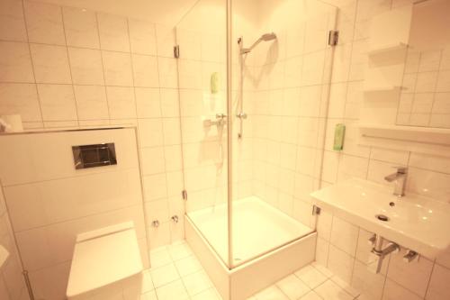 a white bathroom with a shower and a sink at Restaurant Ollex and beds Zimmer 4 in Bliesdorf