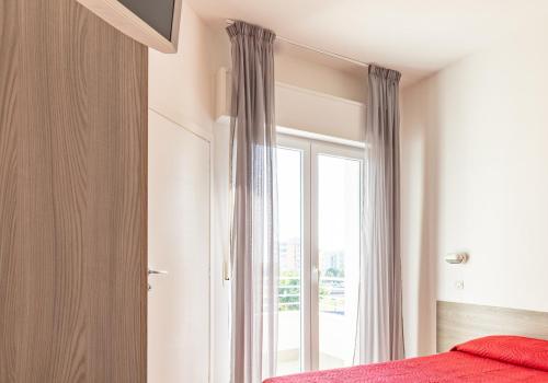 a bedroom with a bed and a large window at Ciccio Hotel in Misano Adriatico