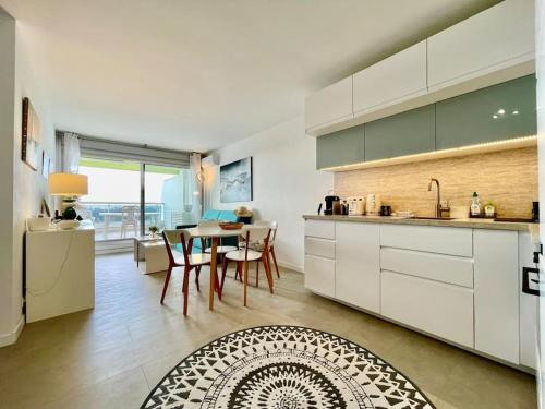 een keuken met witte kasten en een tafel met stoelen bij PGH N25 - Vue Mer, Première Ligne & Parking Privé in La Grande-Motte